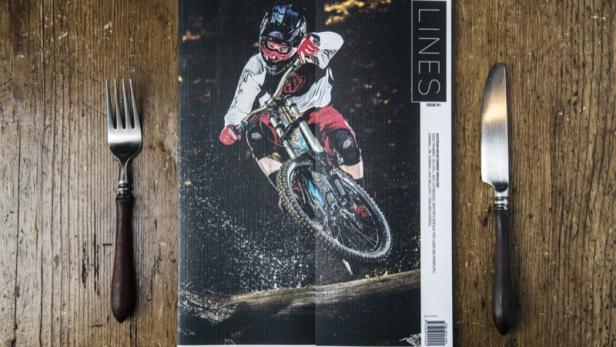 Die Titelseite des „Lines“-Magazins zeigt einen Mountainbiker im Sprung über einen Baumstamm.