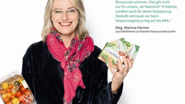 Martina Hörmer, Geschäftsführerin von Ja! Natürlich, hält verpackte Lebensmittel in die Kamera.