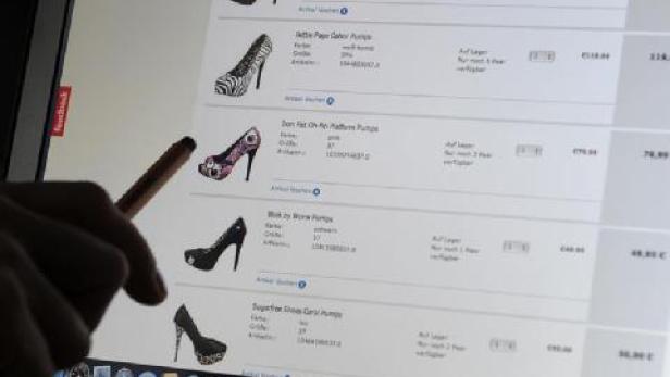 Eine Hand zeigt mit einem Stift auf eine Webseite mit verschiedenen Damenschuhen.