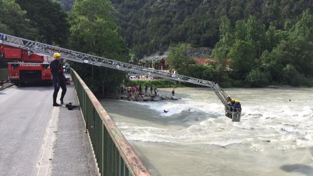 Die Feuerwehr rettet eine Person aus einem reißenden Fluss mit einer Drehleiter.