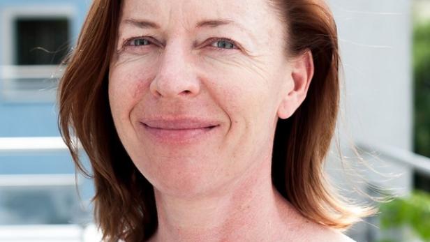 Eine Frau mit rötlichen Haaren lächelt in die Kamera.