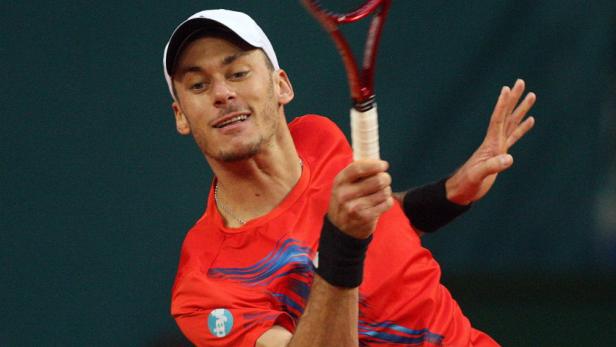 Ein Tennisspieler schlägt einen Ball mit seinem Schläger.