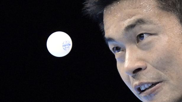 Ein asiatischer Mann blickt auf einen Tischtennisball.