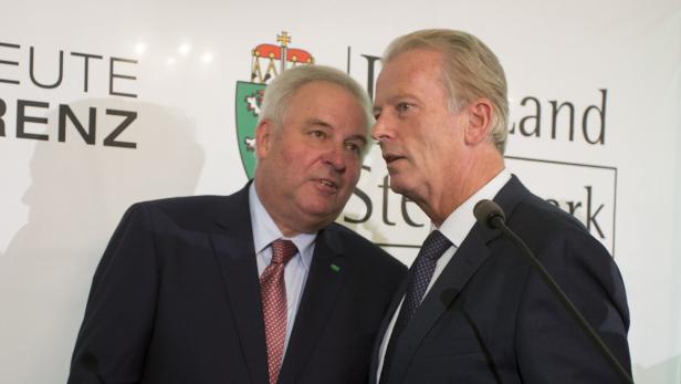 Zwei Männer in Anzügen stehen vor einem Mikrofon und unterhalten sich.