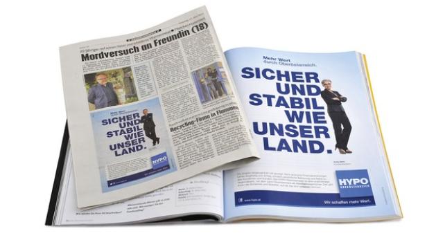 Eine geöffnete Zeitung und Zeitschrift mit einer Anzeige der HYPO Oberösterreich, die für Sicherheit und Stabilität wirbt.