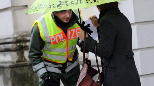 Ein Polizist spricht mit einer Frau unter einem Regenschirm.