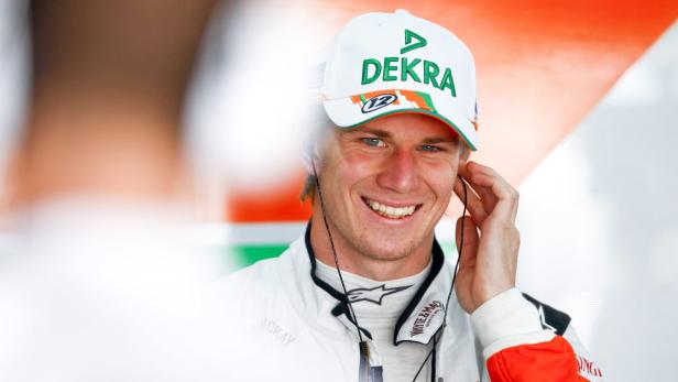 Nico Hülkenberg lächelt mit einer Dekra-Kappe und Kopfhörern.