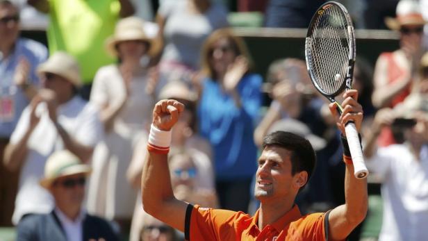 Novak Đoković feiert einen Sieg mit erhobener Faust und Tennisschläger.
