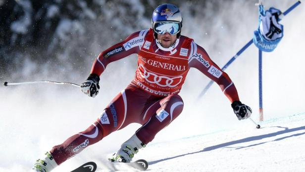 Ein Skirennläufer in roter Rennkleidung fährt einen Hang hinunter.