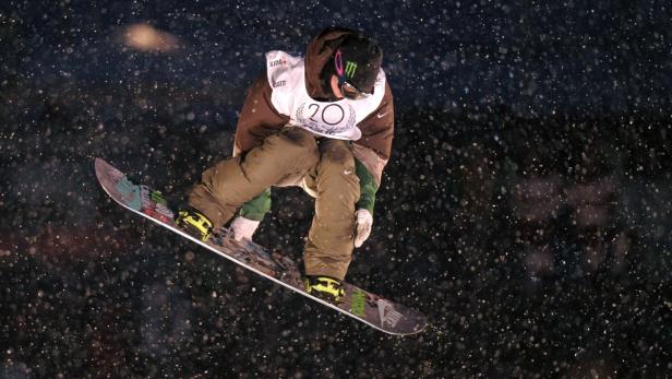 Ein Snowboarder springt in der Nacht durch die Luft.