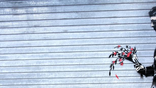 Ein Banksy-Graffiti zeigt einen Mann, der einen Blumenstrauß hält.