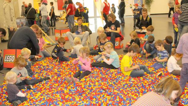 Kinder spielen in einem Becken voller bunter Legosteine.