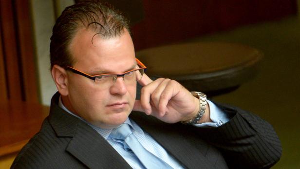 Ein Mann mit Brille und Anzug wirkt nachdenklich.