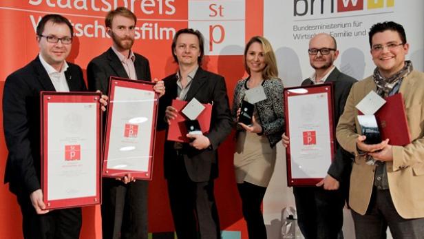 Eine Gruppe von Preisträgern hält Urkunden und Auszeichnungen des Staatspreis Wirtschaftsfilm in den Händen.