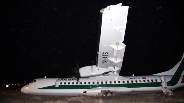 Ein beschädigtes Alitalia-Flugzeug steht nachts auf einem Feld.