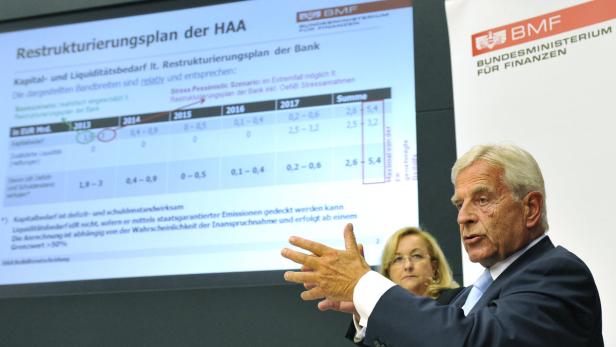 Ein Mann präsentiert einen Restrukturierungsplan der HAA vor Publikum.