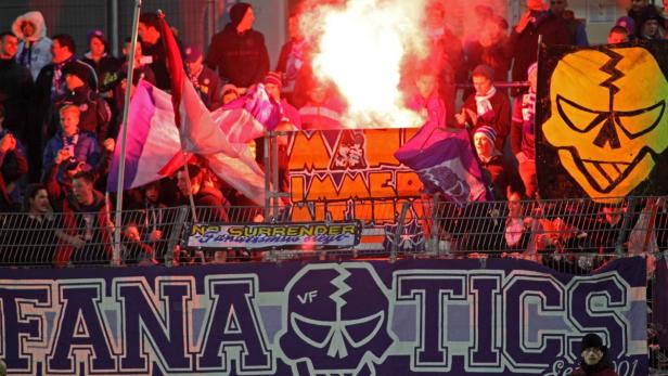 Fußballfans zünden während eines Spiels Rauchbomben und schwenken Fahnen.