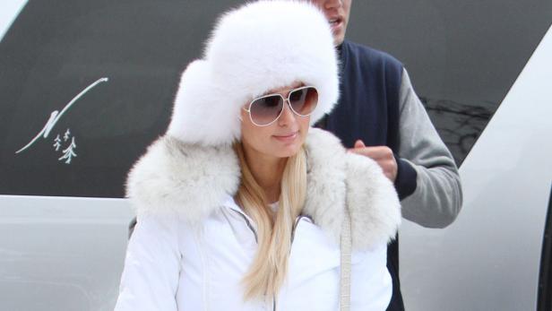 Paris Hilton trägt eine weiße Pelzmütze und eine passende Jacke.