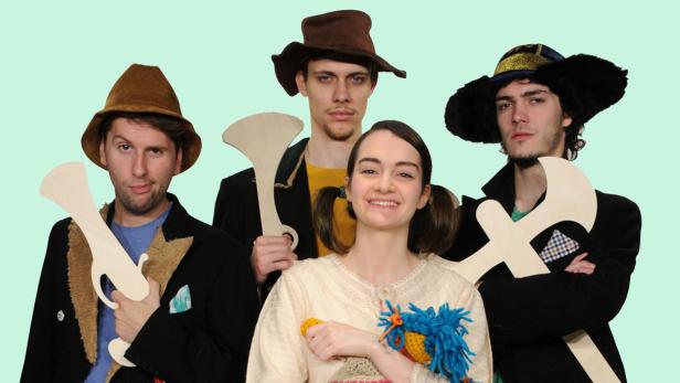 Fünf Personen mit Hüten posieren mit hölzernen Requisiten für ein Foto.