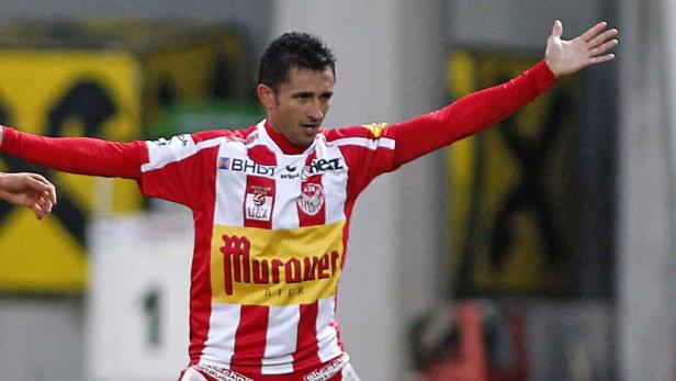 Ein Fußballspieler im rot-weiß gestreiften Trikot jubelt mit erhobenen Armen.