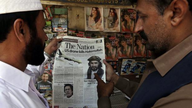 Zwei Männer betrachten eine Titelseite der Zeitung „The Nation“ mit der Schlagzeile über den Tod von Hakimullah durch eine US-Drohne.