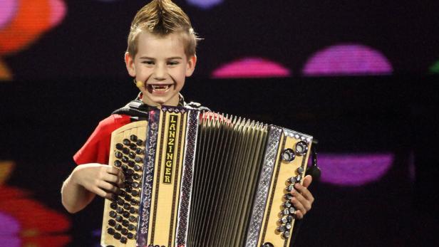 Ein lächelnder Junge mit Irokesenschnitt spielt auf einer Steirischen Harmonika der Marke Lanzinger.