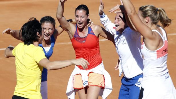 Italienische Tennisspielerinnen feiern einen Sieg auf dem Platz.