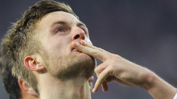 Ein Mann mit Bart blickt nach oben und berührt seine Lippen mit den Fingern.
