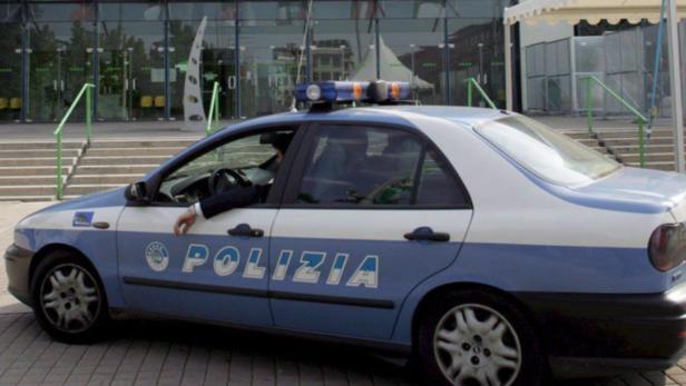 Ein blau-weißes Polizeiauto steht vor einem Gebäude.