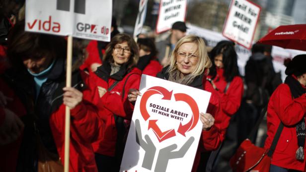 Demonstranten fordern mit Schildern eine Aufwertung sozialer Arbeit.