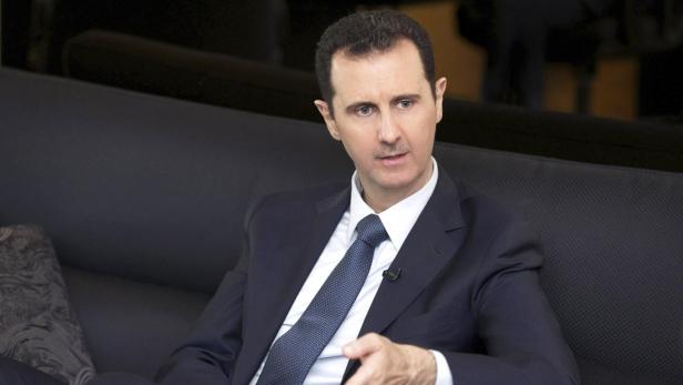 Baschar al-Assad sitzt in einem dunklen Anzug auf einem Sofa.