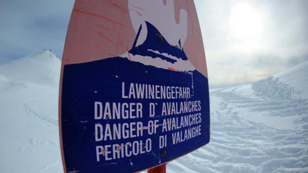 Ein Schild warnt vor Lawinengefahr in den Bergen.