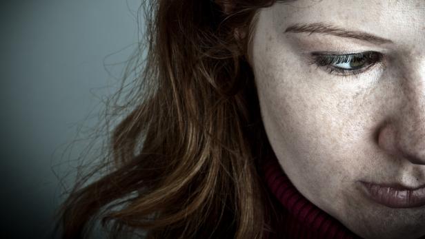 Das Porträt einer Frau mit braunen Haaren und einem roten Rollkragenpullover.