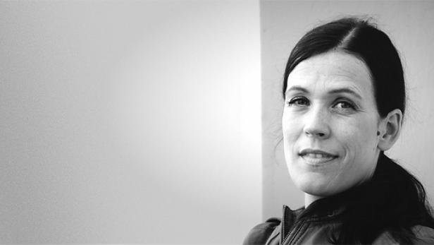Schwarzweißporträt einer Frau mit dunklen Haaren und einem leichten Lächeln.