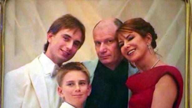 Ein Familienporträt mit zwei jungen Männern, einem älteren Mann und einer Frau in einem roten Kleid.
