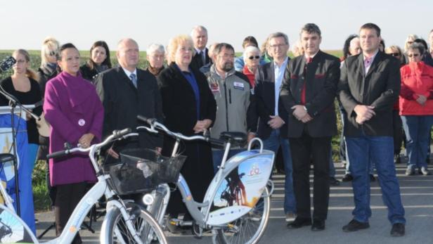 Eine Gruppe von Menschen steht neben Fahrrädern im Freien.