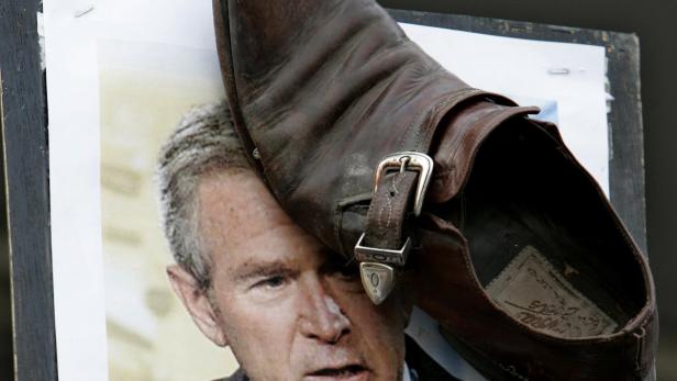 Ein brauner Schuh liegt auf einem Porträt von George W. Bush.