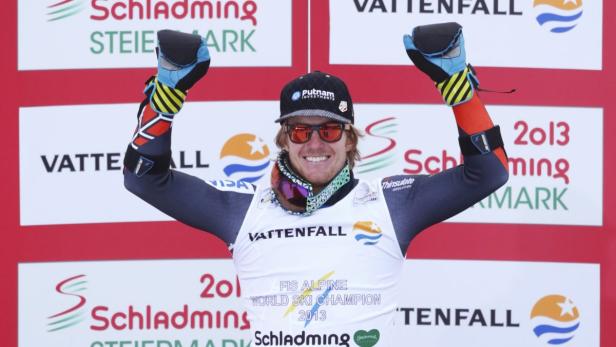 Ein lächelnder Skirennläufer mit Sonnenbrille und Mütze feiert einen Sieg in Schladming.