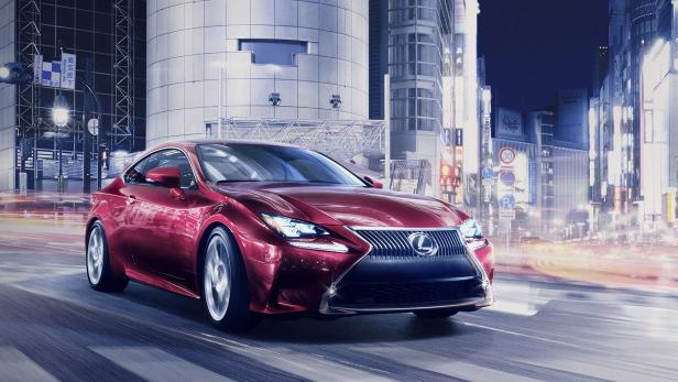Ein roter Lexus fährt durch eine belebte Stadt bei Nacht.