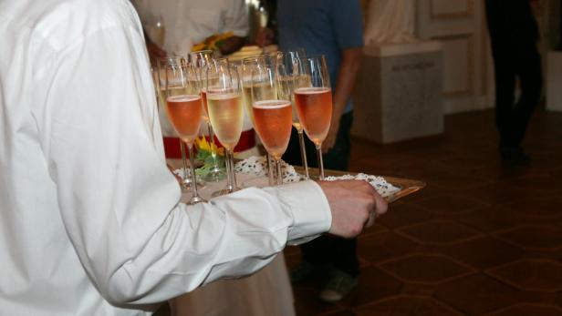 Ein Kellner serviert eine Auswahl an Sektgläsern auf einem Tablett.