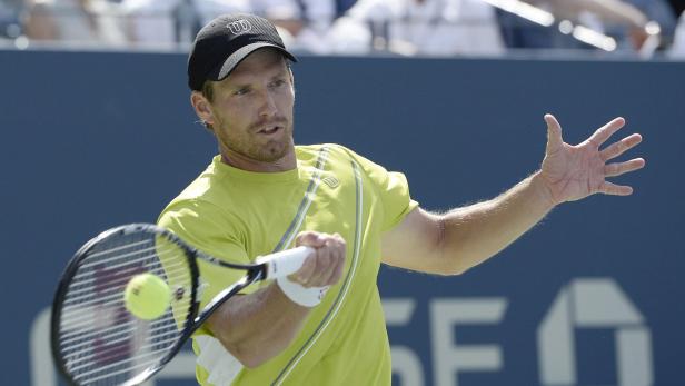 Ein Tennisspieler schlägt einen Ball mit seinem Schläger.