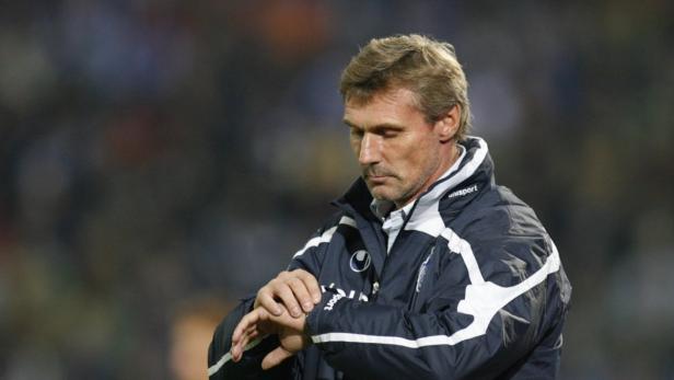 Ein Mann in einer Sportjacke blickt auf seine Armbanduhr.