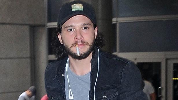 Kit Harington mit Zigarette im Mund und Kopfhörern um den Hals.