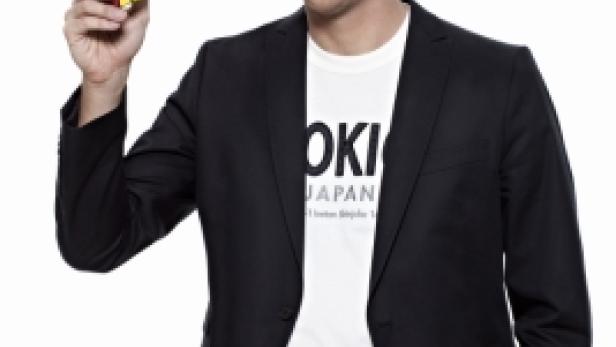 Ein Mann im Blazer hält einen Rubik's Cube in der Hand.