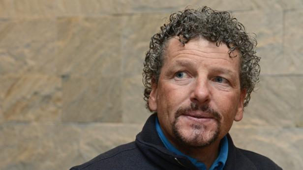 Ein Mann mit lockigem Haar und Bart blickt nach links.