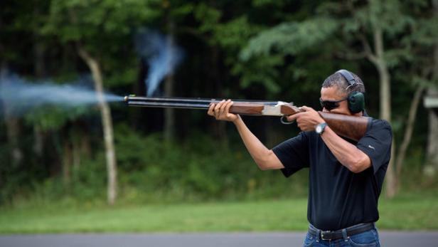 Barack Obama schießt mit einer Flinte auf einem Schießstand.