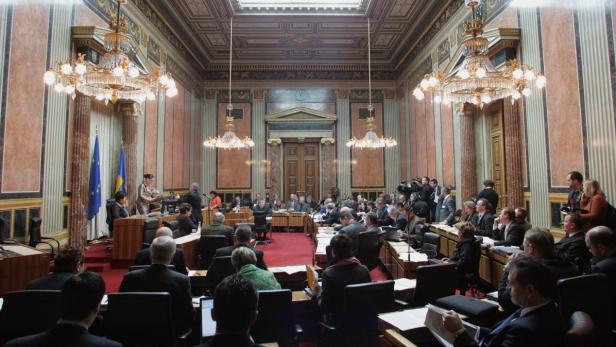 Eine Sitzung im prunkvollen Saal mit zahlreichen Teilnehmern und Flaggen.