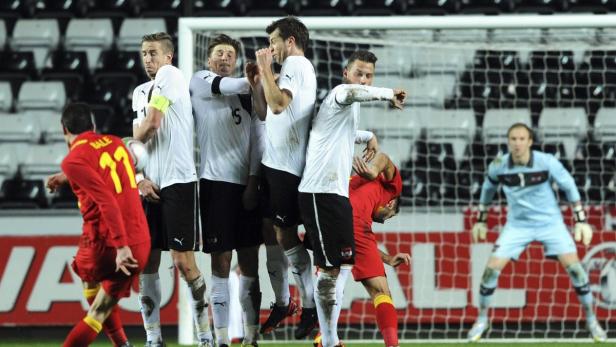 Eine Gruppe Fußballspieler bildet eine Mauer während eines Spiels.