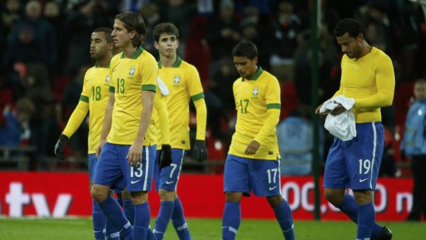 Mehrere brasilianische Fußballspieler in gelben Trikots und blauen Hosen stehen auf dem Spielfeld.