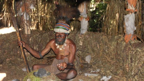 Hexenjagd in Papua-Neuguinea wieder auf Vormarsch Ein Mann mit Kopfschmuck und traditioneller Kleidung sitzt in einer Hütte.